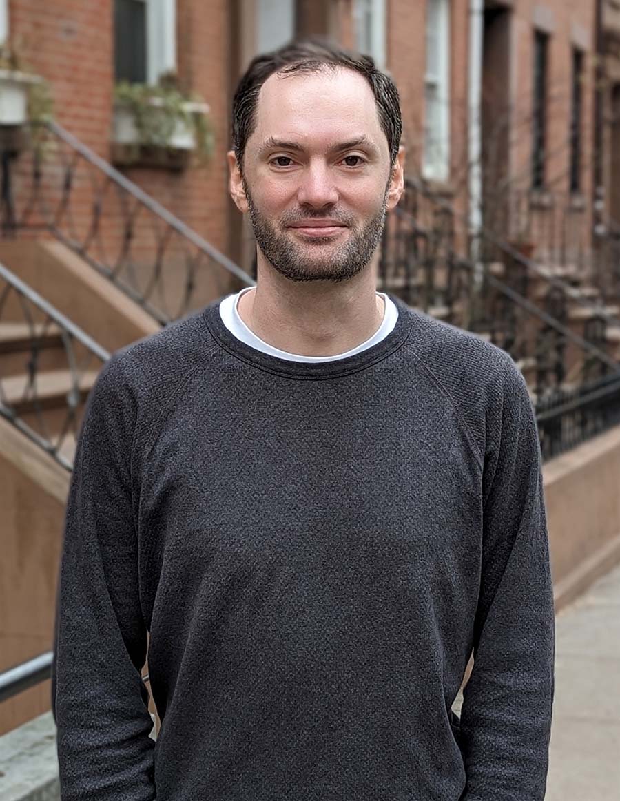 Neil Holroyde in a dark sweater standing on the street